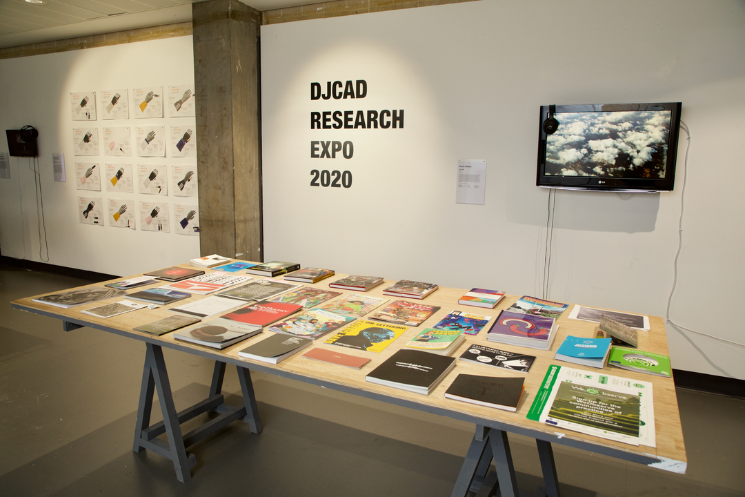 DJCAD research expo with a table covered in various books